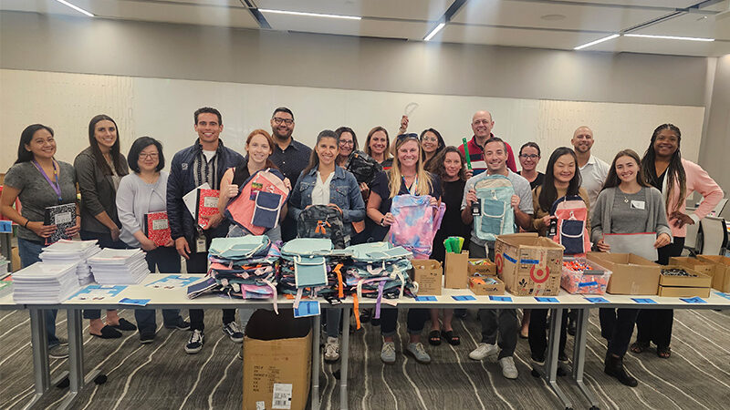 Employees putting together back-to-school backpacks for students.